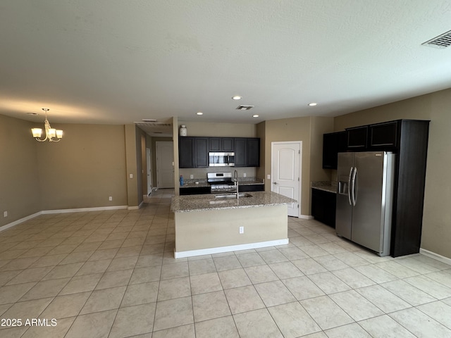 kitchen with visible vents, a sink, light stone counters, a notable chandelier, and stainless steel appliances