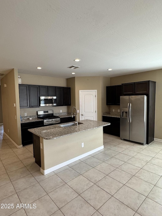 kitchen with visible vents, a sink, light stone counters, stainless steel appliances, and light tile patterned flooring