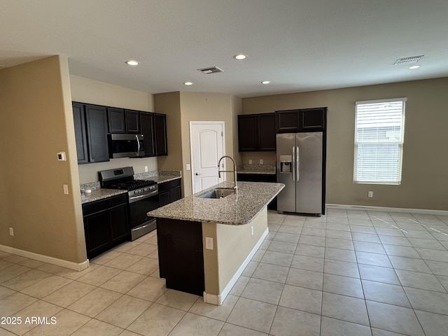 kitchen with visible vents, light stone counters, a sink, light tile patterned floors, and stainless steel appliances