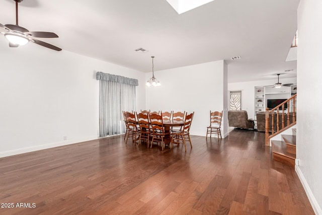 dining room with wood finished floors, stairway, ceiling fan with notable chandelier, and visible vents