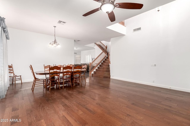 unfurnished dining area featuring visible vents, stairway, wood finished floors, and ceiling fan with notable chandelier