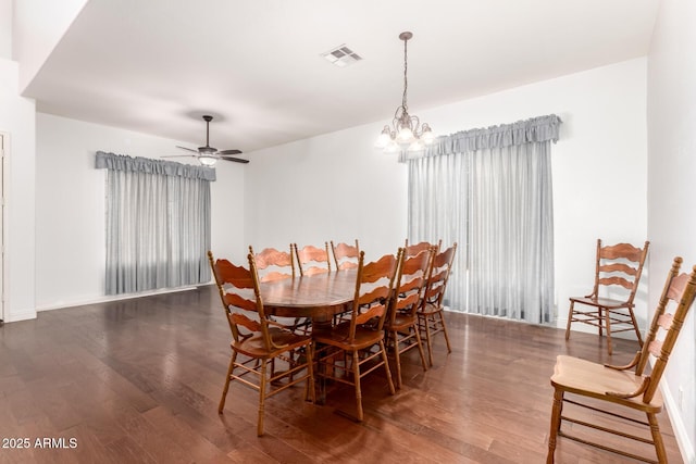 dining space featuring visible vents, ceiling fan with notable chandelier, baseboards, and wood finished floors