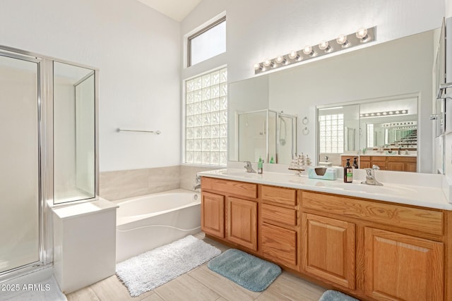 full bath featuring a sink, a garden tub, double vanity, and a shower stall