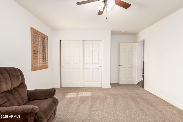 living area featuring baseboards, a ceiling fan, and carpet floors