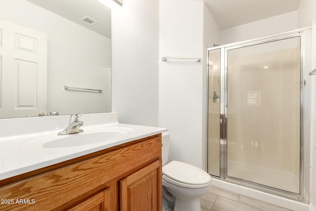 bathroom featuring vanity, toilet, visible vents, and a stall shower