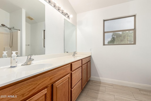 bathroom with double vanity, visible vents, baseboards, and a sink