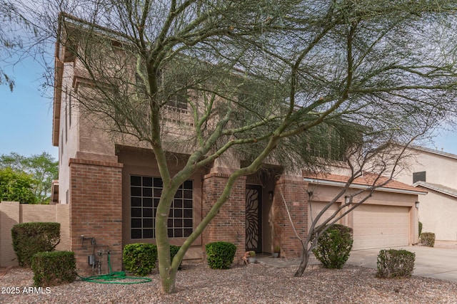 view of front of home featuring brick siding, stucco siding, and concrete driveway