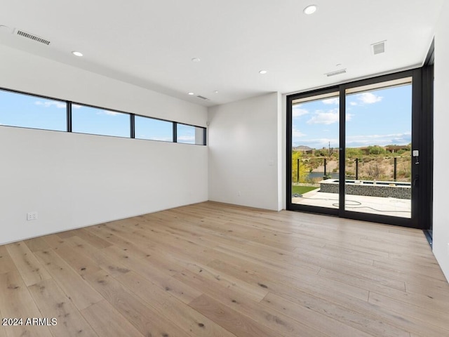 spare room featuring light hardwood / wood-style floors and floor to ceiling windows