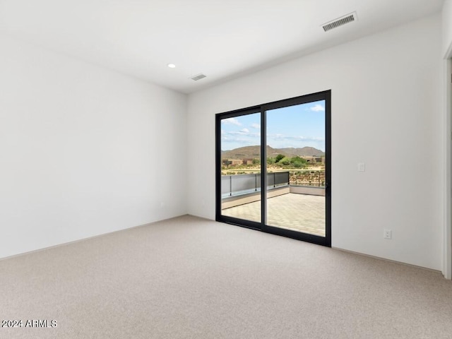 unfurnished room with a mountain view and light colored carpet