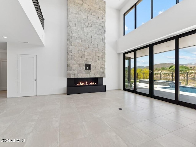 unfurnished living room with a fireplace, light tile patterned floors, and a high ceiling