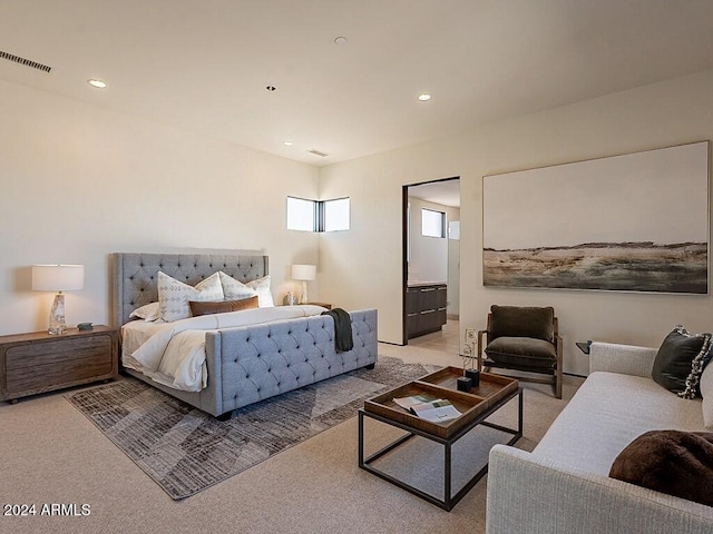 bedroom featuring ensuite bathroom and light carpet