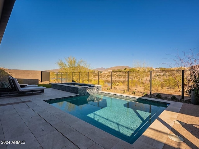 view of swimming pool featuring a mountain view, a patio area, and an in ground hot tub