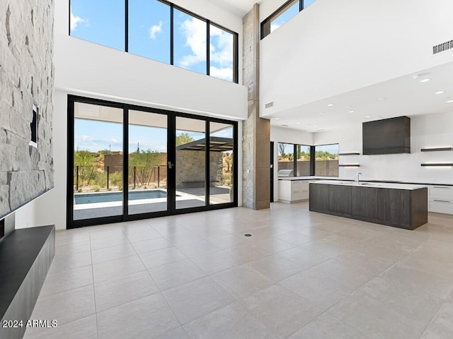 unfurnished living room featuring a towering ceiling and light tile patterned floors