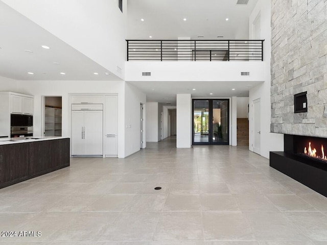 interior space with a towering ceiling, a fireplace, and light tile patterned floors