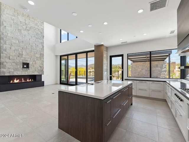 kitchen featuring white cabinets, a wealth of natural light, a center island with sink, and a fireplace