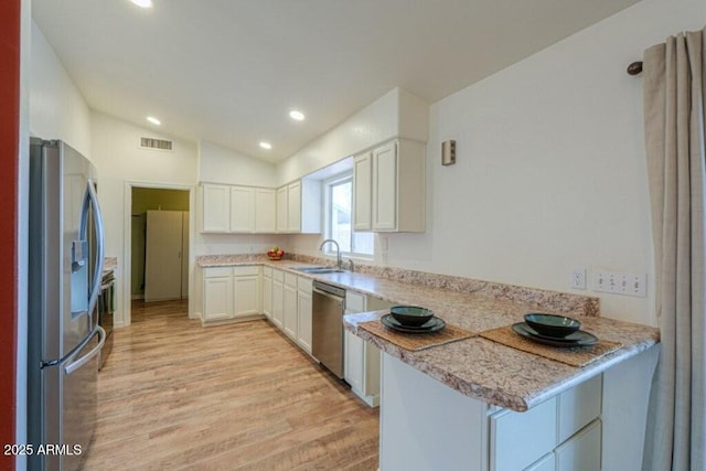 kitchen with visible vents, white cabinets, lofted ceiling, appliances with stainless steel finishes, and a sink