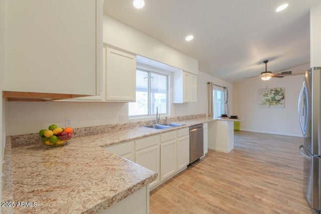 kitchen with white cabinetry, stainless steel appliances, a sink, and light countertops