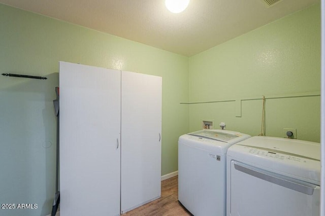 clothes washing area with laundry area, light wood-type flooring, and washing machine and dryer