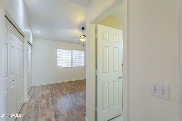 hall featuring light wood-style flooring and baseboards