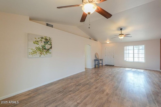 unfurnished living room featuring arched walkways, wood finished floors, visible vents, baseboards, and vaulted ceiling