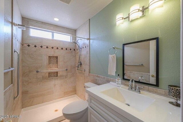 full bathroom featuring toilet, a stall shower, tile walls, and vanity