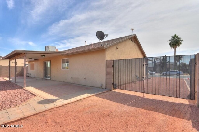 exterior space featuring a patio, fence, a gate, and stucco siding