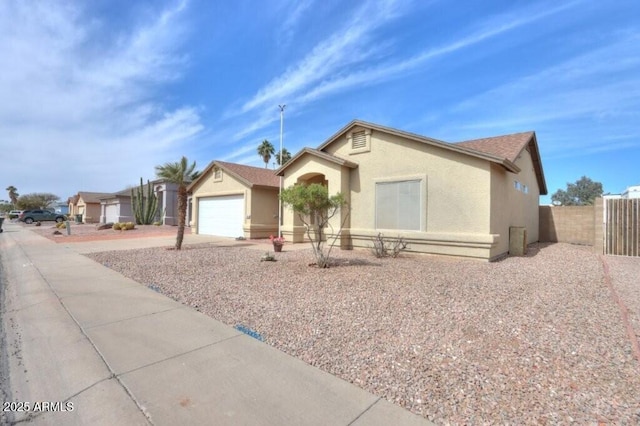 ranch-style house featuring driveway, a garage, fence, and stucco siding