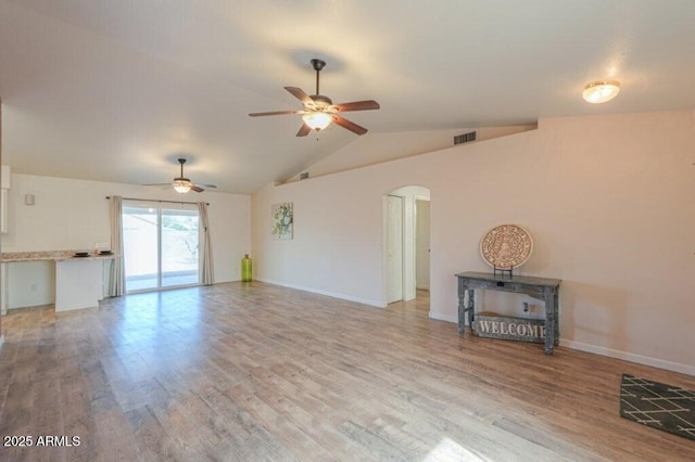 unfurnished living room featuring lofted ceiling, light wood-type flooring, visible vents, and arched walkways