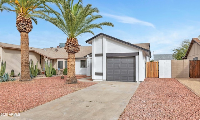 mid-century inspired home featuring a garage, driveway, fence, and stucco siding