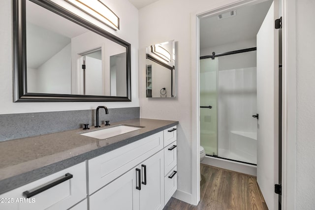 full bath featuring a stall shower, visible vents, toilet, wood finished floors, and vanity