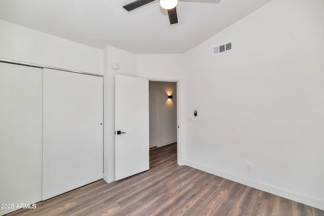 unfurnished bedroom with dark wood finished floors, a closet, visible vents, a ceiling fan, and baseboards