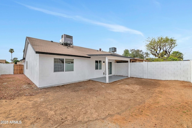 rear view of house featuring a patio area, a fenced backyard, central AC, and stucco siding