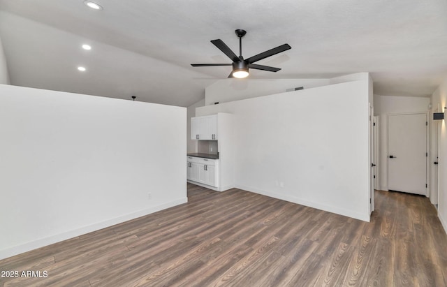 interior space with lofted ceiling, ceiling fan, dark wood finished floors, and baseboards