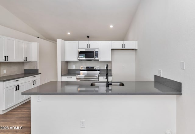 kitchen featuring appliances with stainless steel finishes, dark countertops, white cabinets, and a sink