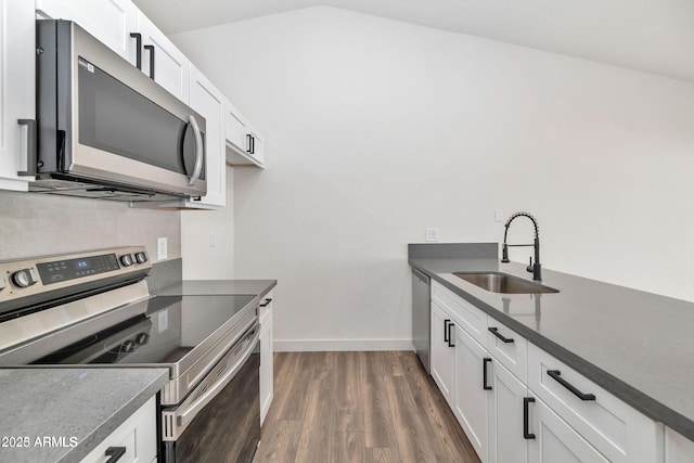 kitchen with white cabinets, dark countertops, dark wood-type flooring, stainless steel appliances, and a sink