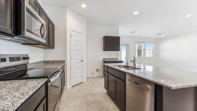 11891 E Cliffrose Ln, Florence, AZ 85132 - kitchen featuring appliances with stainless steel finishes, light stone countertops, recessed lighting, a kitchen island with sink, and dark brown cabinetry