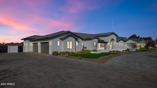 view of front of house with driveway, an attached garage, a tiled roof, and stucco siding