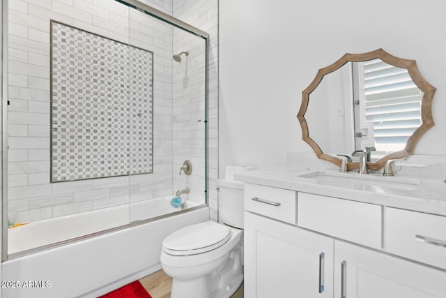 bathroom with toilet, enclosed tub / shower combo, and vanity