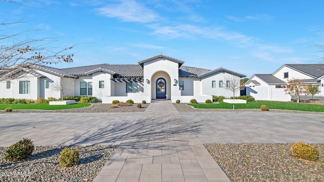 view of front of home featuring a tiled roof, fence, a residential view, and stucco siding