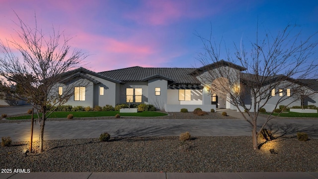 view of front facade with driveway, a tile roof, and stucco siding