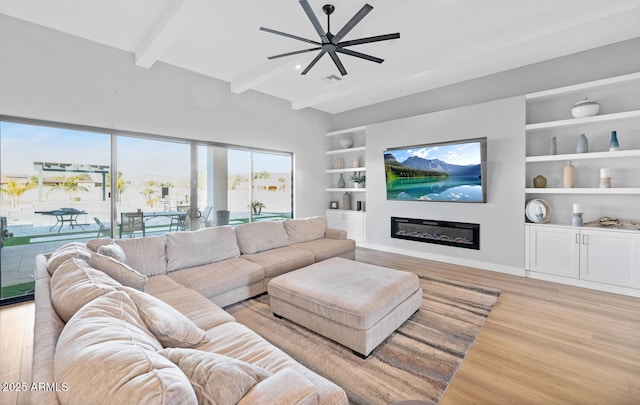 living room with ceiling fan, vaulted ceiling with beams, light wood-style flooring, built in features, and a glass covered fireplace