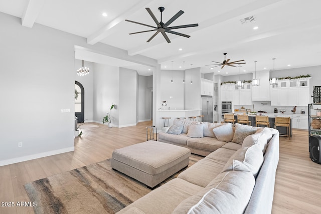 living area featuring light wood-style floors, baseboards, visible vents, and beam ceiling