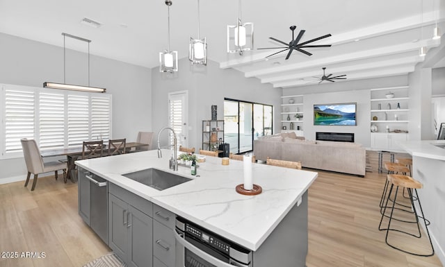 kitchen featuring light stone countertops, pendant lighting, a sink, and gray cabinetry