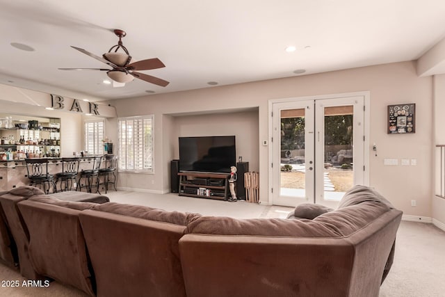 carpeted living room featuring bar, french doors, ceiling fan, and plenty of natural light