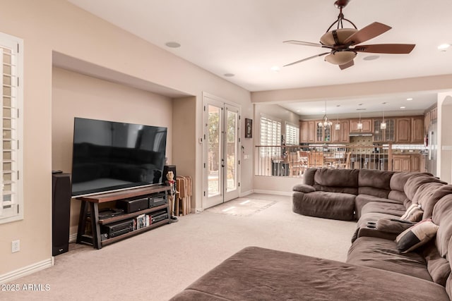 living room featuring ceiling fan with notable chandelier and light colored carpet