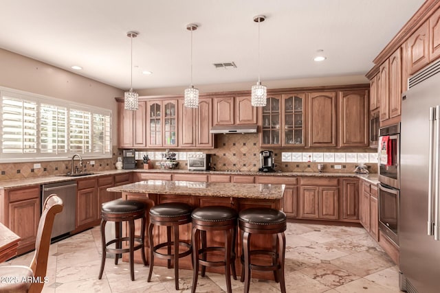 kitchen with appliances with stainless steel finishes, hanging light fixtures, a center island, and sink