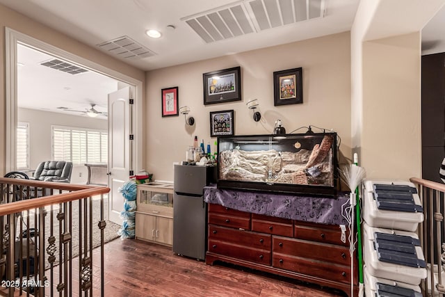 bedroom featuring stainless steel fridge and dark hardwood / wood-style flooring