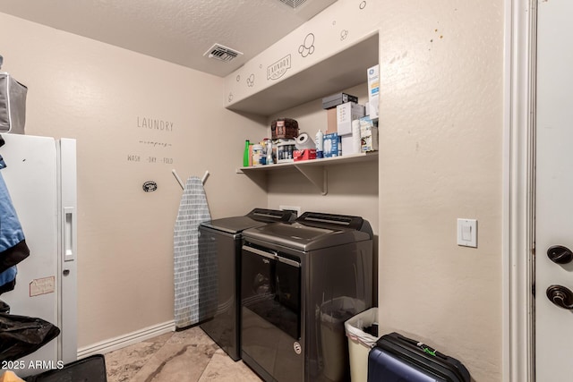 clothes washing area with a textured ceiling and washer and clothes dryer