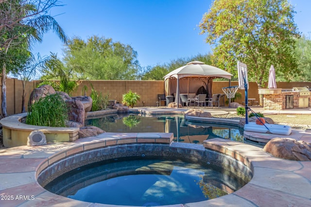 view of swimming pool with a patio area, an outdoor kitchen, a gazebo, a bar, and an in ground hot tub