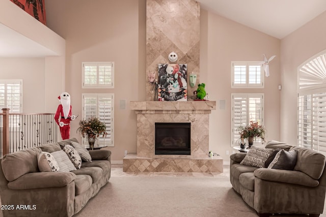 carpeted living room with a premium fireplace and a towering ceiling